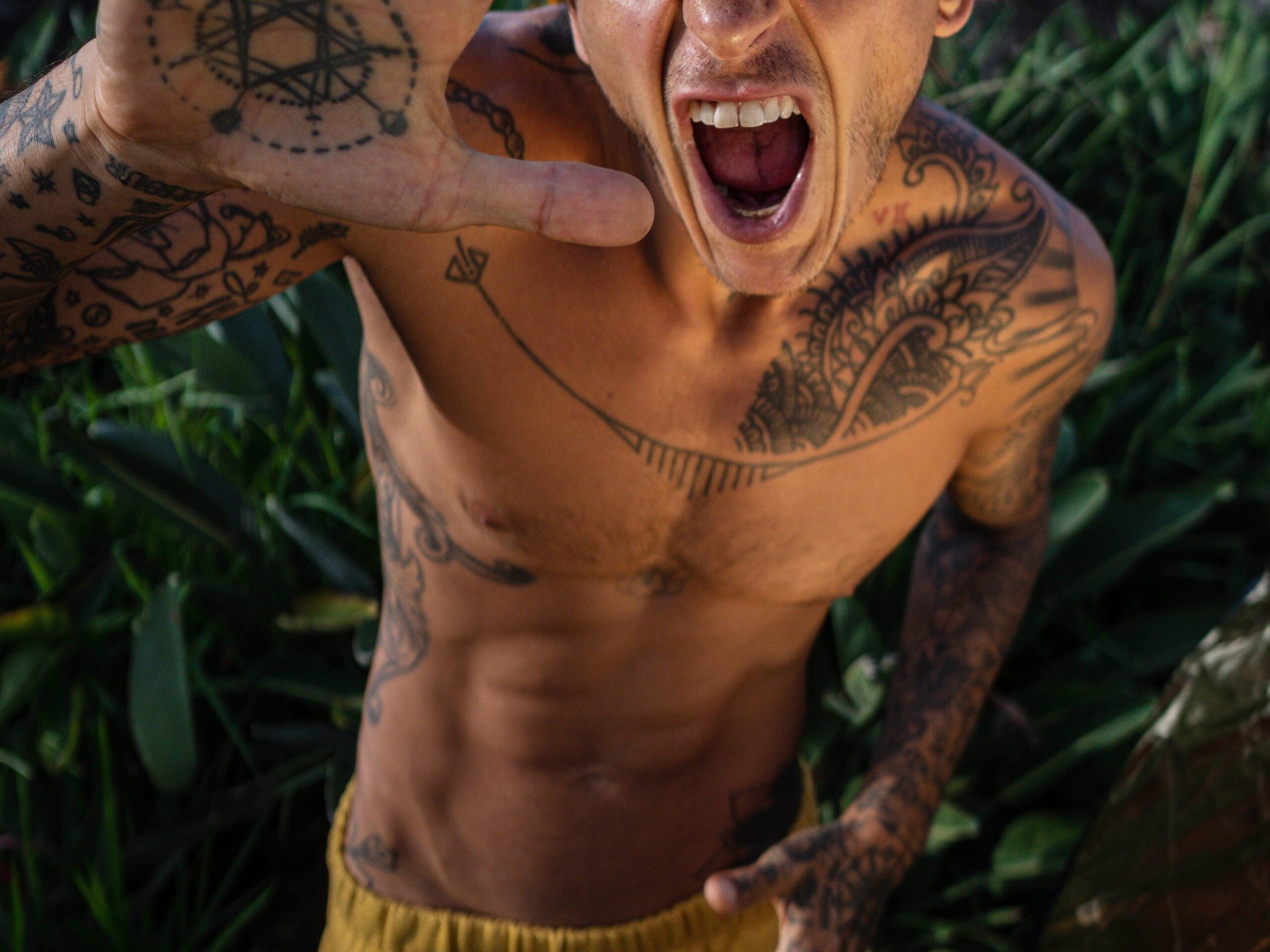 Shirtless man with tattoos and a cap yelling energetically outdoors in São Paulo telling yelling at his gay hookup partner to turn him on as erotic humilation kink fetish